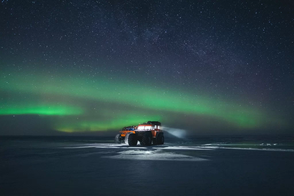 A mesmerizing display of Northern Lights (Aurora Borealis) illuminating the night sky with shades of green and purple over snowy landscapes.