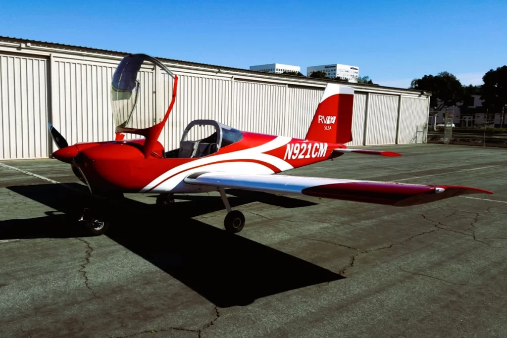 Red Vans RV-12 aircraft parked with its canopy open, showcasing its sleek design and lightweight structure