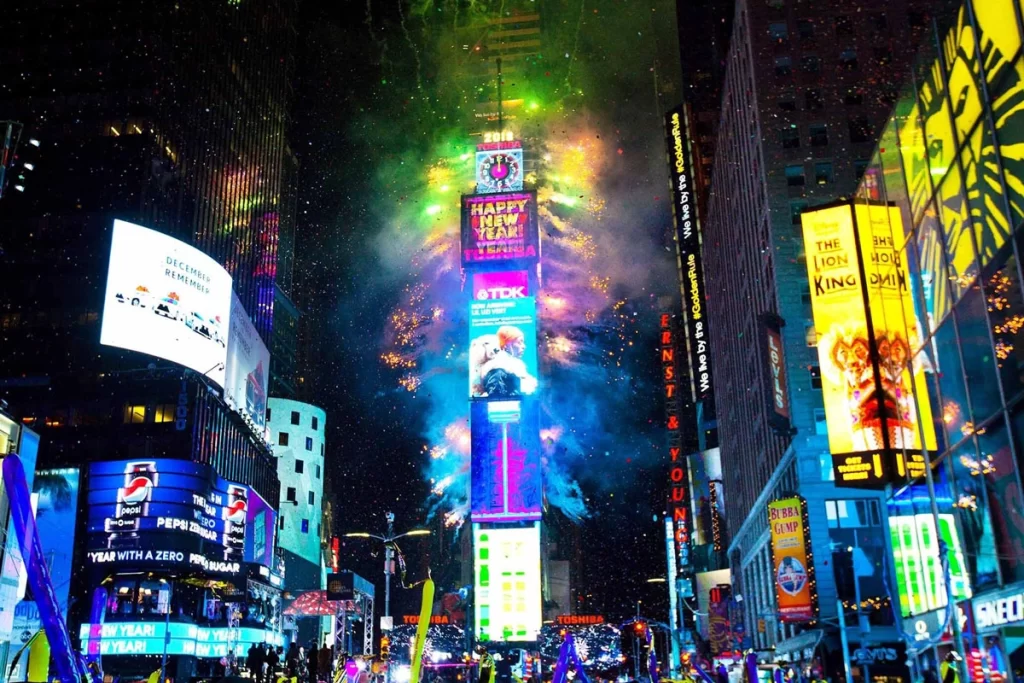 Times Square in New York City illuminated with colorful lights and fireworks during the New Year’s Eve celebration, with the iconic Ball Drop and crowds gathered to welcome the New Year