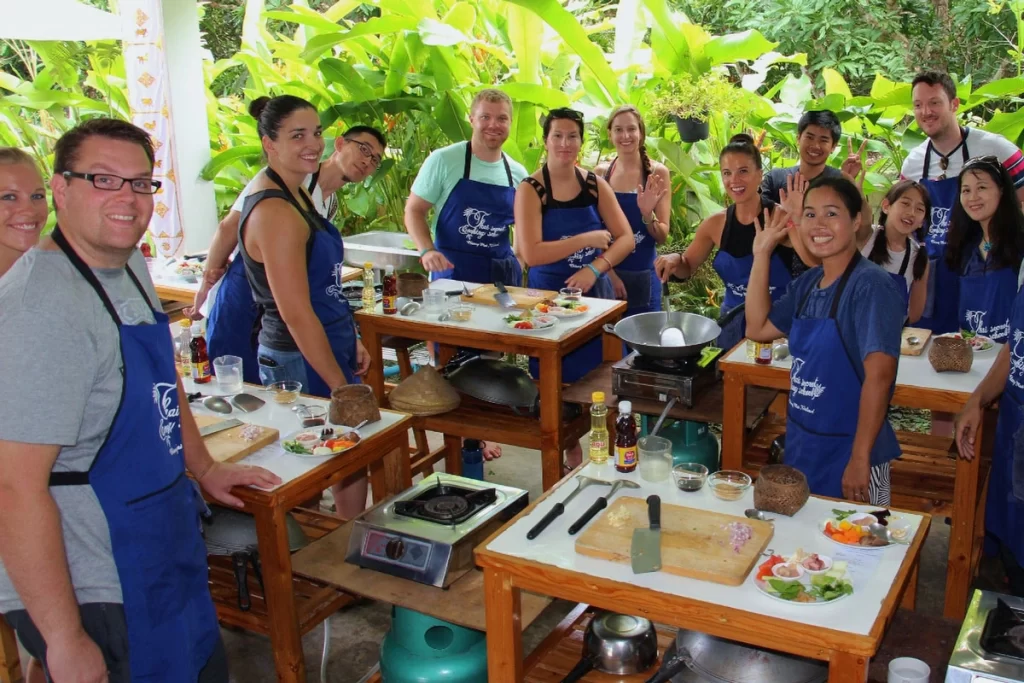 An American traveler preparing Tom Yum soup during a Thai cooking class, surrounded by fresh herbs and spices in a modern kitchen