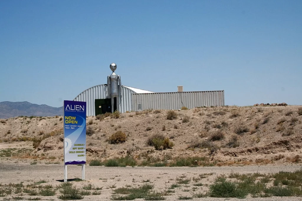 The Alien Research Center in Nevada with a giant silver alien statue at the entrance, surrounded by desert terrain.