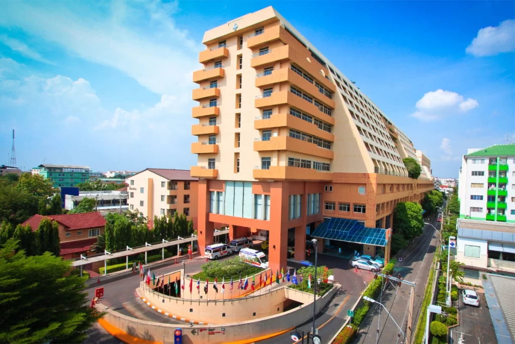 Vejthani Hospital building in Bangkok, Thailand, with a modern design and international flags displayed at the entrance