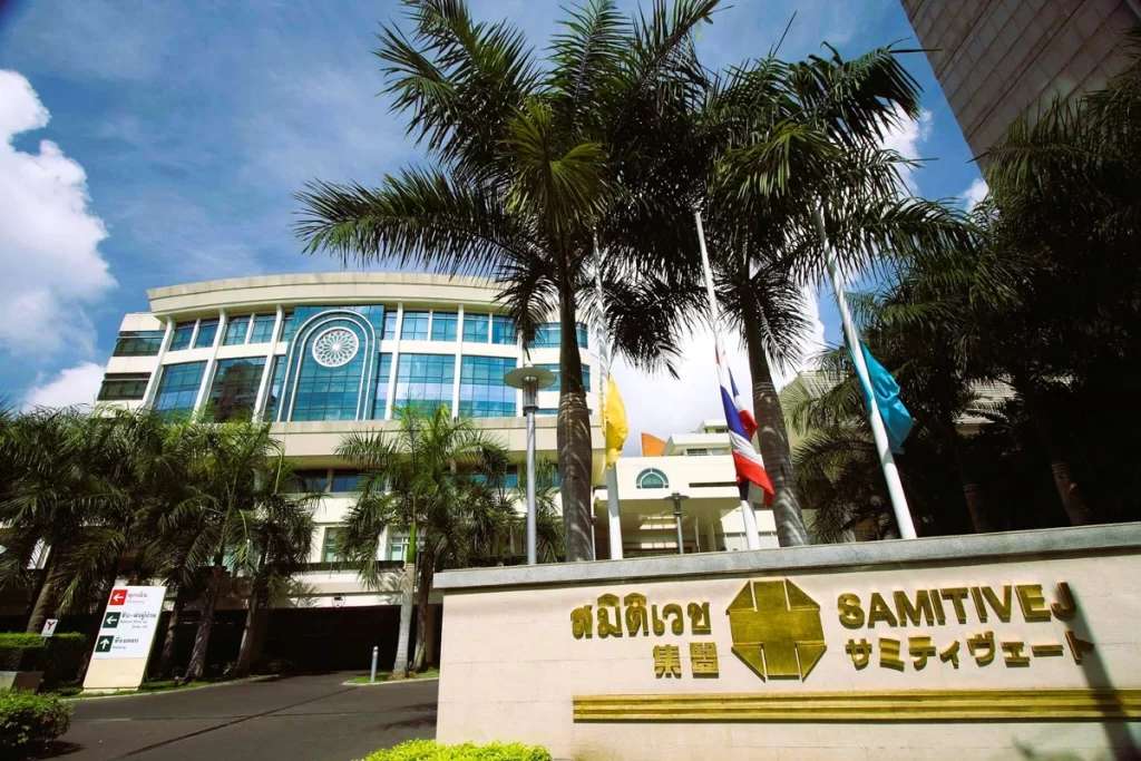 Samitivej Hospital entrance at night with illuminated signs and flags, highlighting its welcoming atmosphere and premium healthcare services