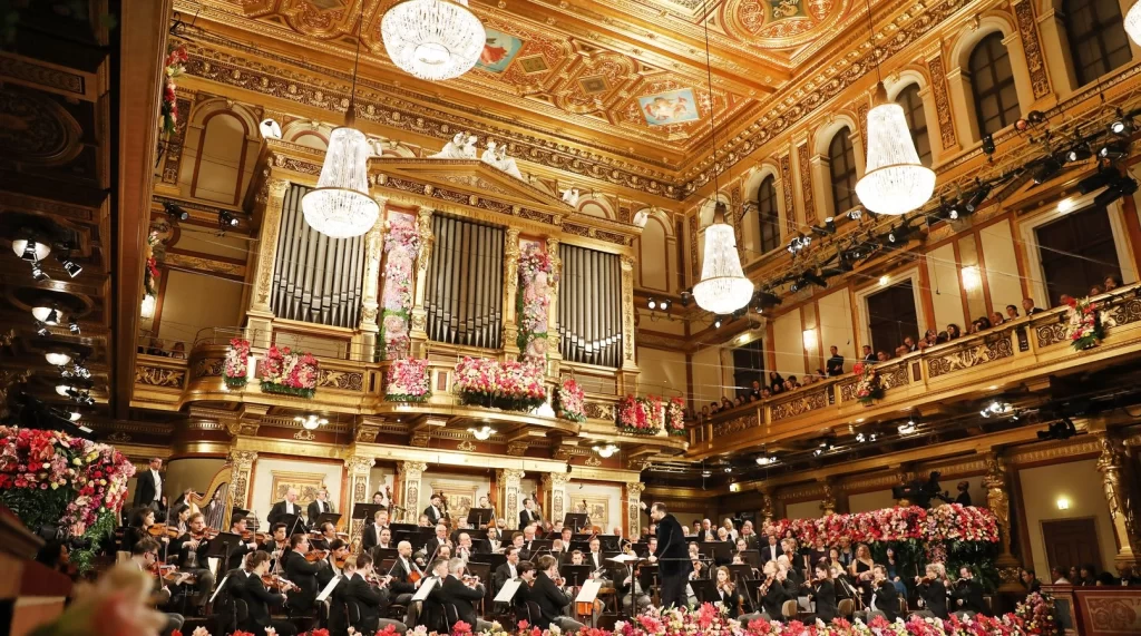 The Vienna Philharmonic performing in the opulent Golden Hall of the Musikverein, surrounded by elegant decor and an attentive audience.