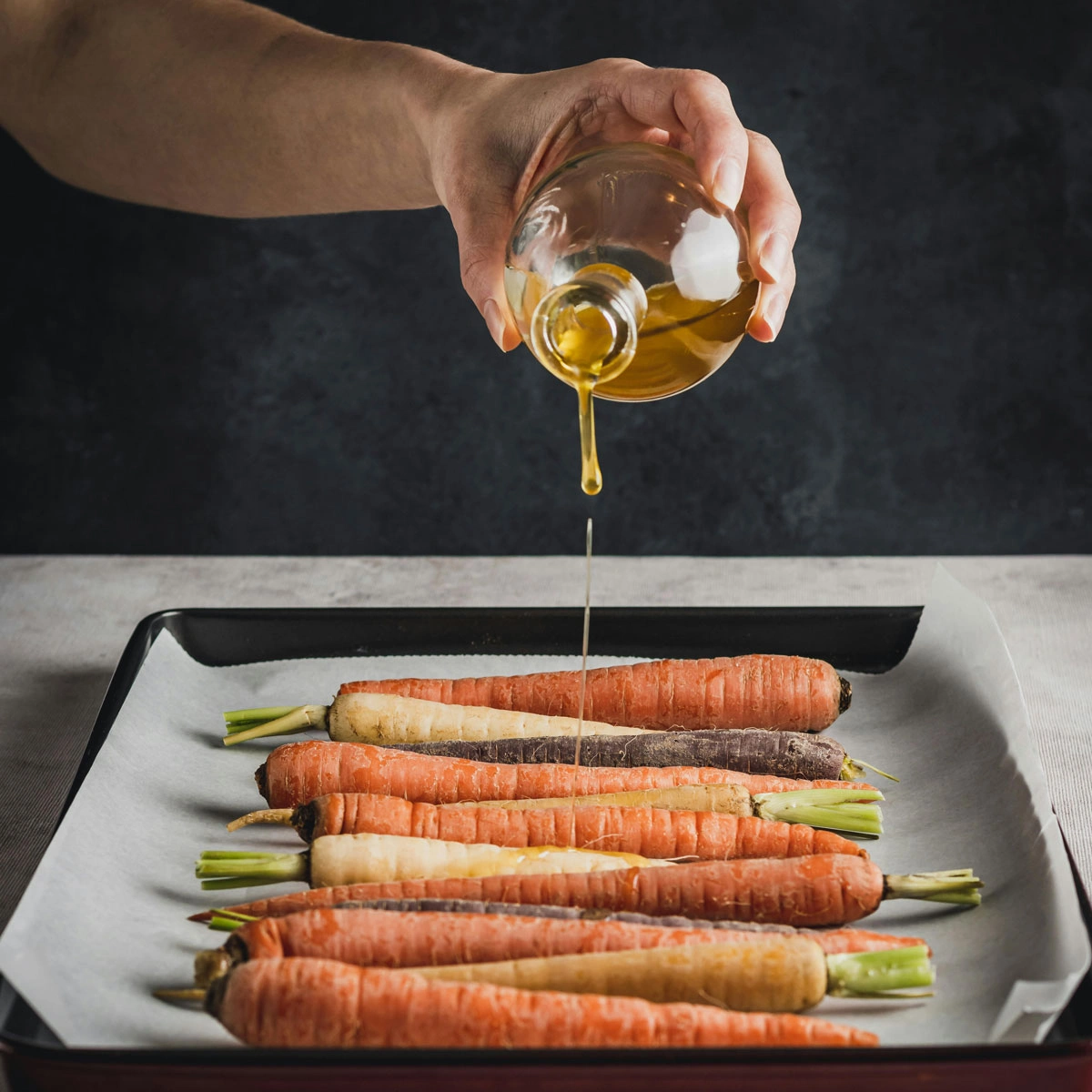 DIY cold-pressed carrot oil in a dark glass bottle with fresh carrots and carrier oil, showcasing its natural benefits for skincare and hair care