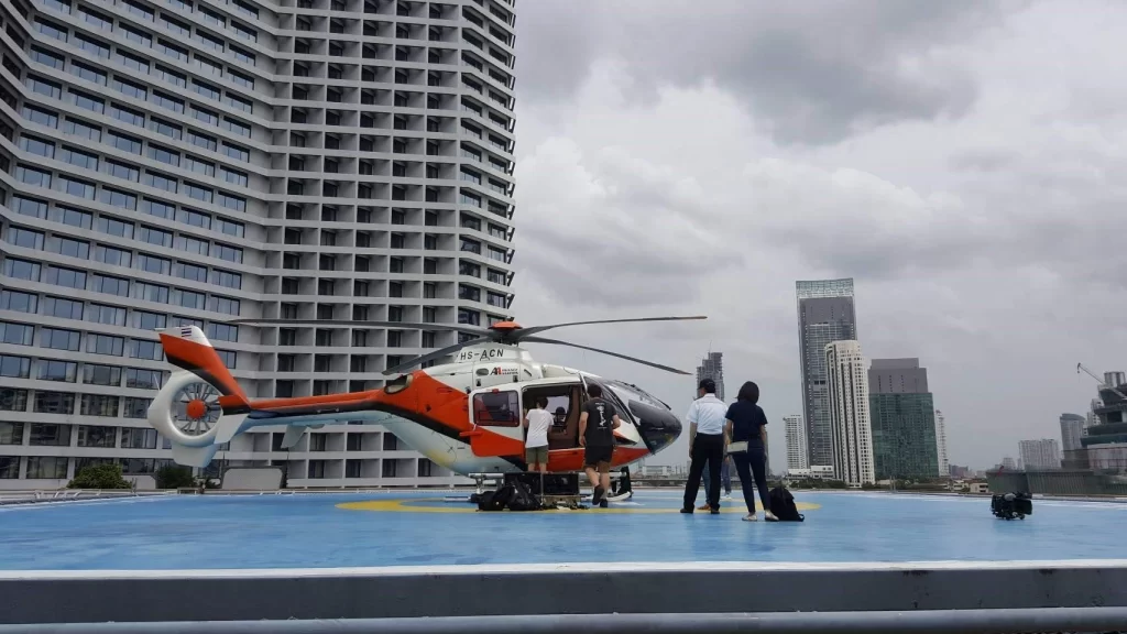 Film production crew boarding a helicopter for a shoot, arranged by THAITAXISERVICES™