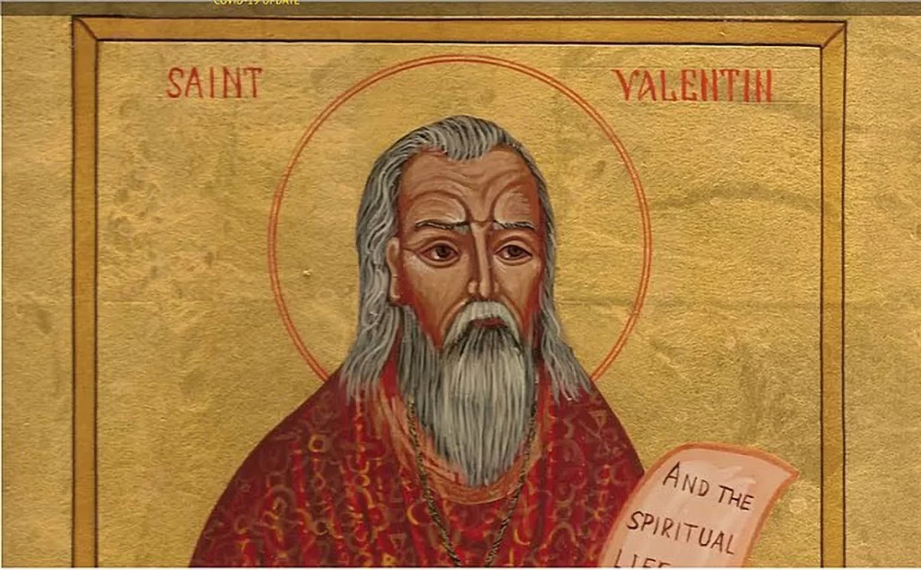 An iconographic depiction of Saint Valentine with a golden background, featuring a halo around his head, wearing a red robe, and holding a scroll with text. Caption: An artistic representation of Saint Valentine, the legendary figure associated with love and devotion, often celebrated on February 14.