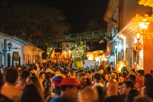 Vibrant street party during Rio Carnival with crowds of people dressed in colorful costumes, dancing, and celebrating under the sun.