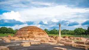 Ruins of Vaishali, India, featuring an ancient stupa and Ashokan pillar under a blue sky